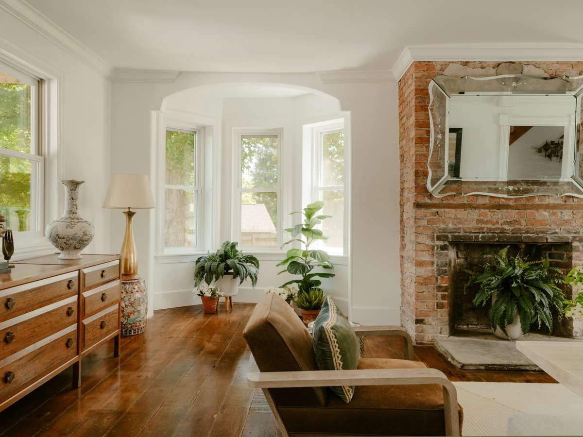 Comfortable, classic living room with a timber dresser, houseplants and a bay window